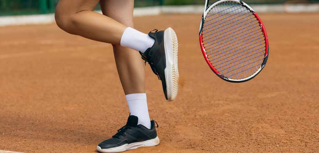 Tennisschuhe - Dame mit Tennisschuhen und Tennisschlägern - Aufnahme der Füße